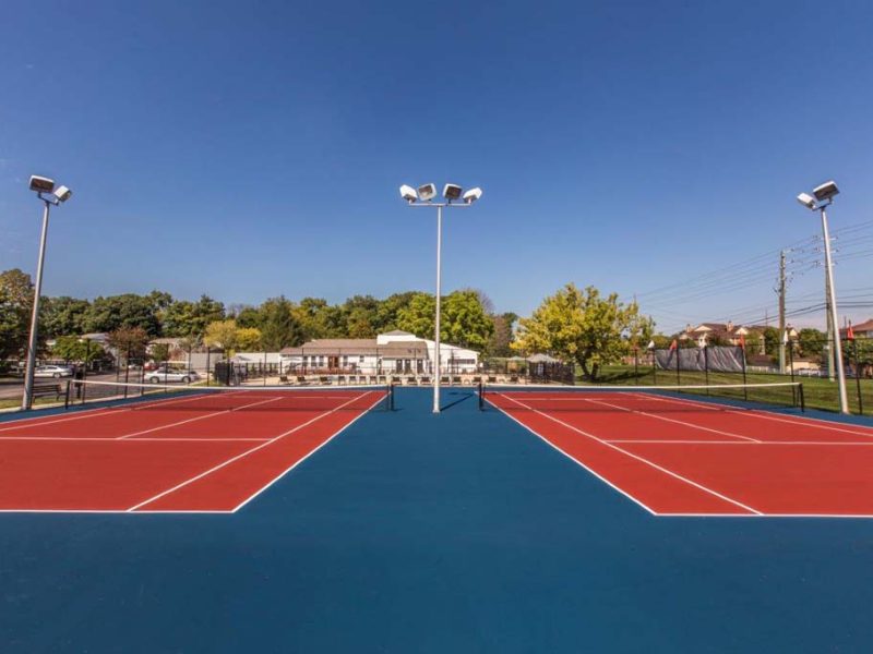 This image shows the premium community amenities, showing the ideal two-lighted tennis court a spacious area for both players and audiences.